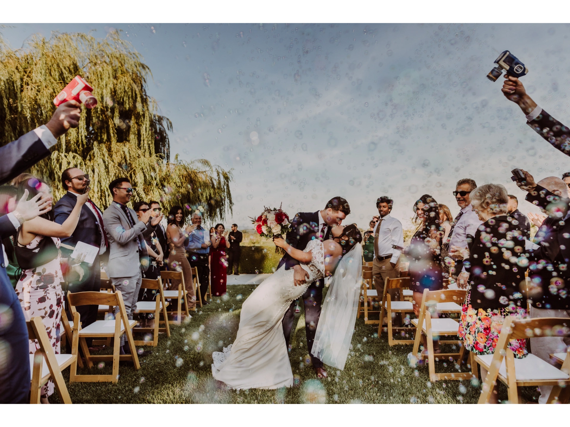 Outdoor wedding ceremony with guests celebrating with bubbles
